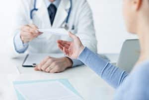Arzt in seinem Büro, der dem Patienten ein ärztliches Rezept gibt. Arzt in seinem Büro, der dem Patienten ein ärztliches Rezept gibt, wodurch er eine Kostenerstattung für seine Einlagen erhält.